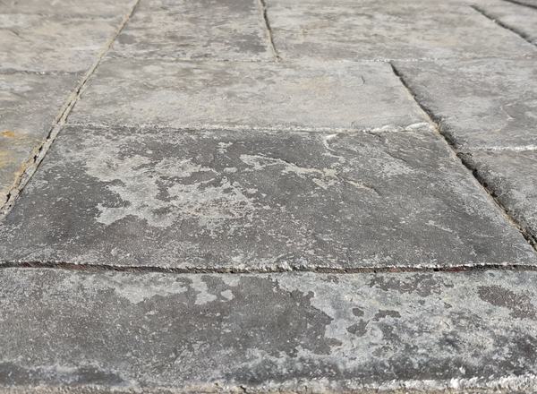 Stamped concrete with white, patchy sealer that has let go of the surface