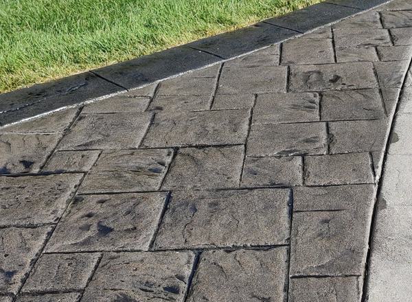 Stamped concrete half sealed with rich color, half faded and chalky